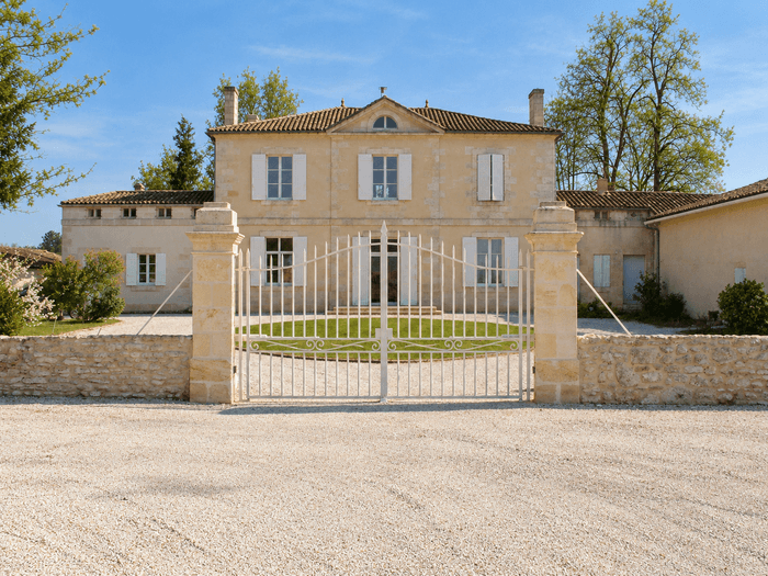 Façade principale du château viticole des Domaines Pedro, demeure familiale en pierre avec portail d’entrée, au cœur du vignoble du Médoc.